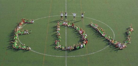 Los niños y niñas de la Escuela Deportiva de Verano de la UJA componiendo las letras EDV en el campo de fútbol