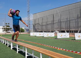 Participantes con balon medicinal sobre banco de equilibrio