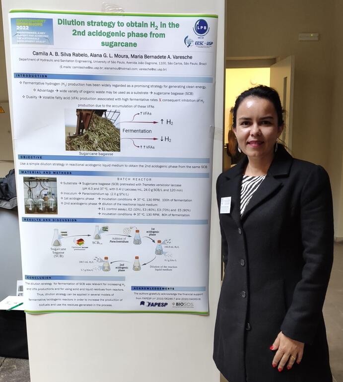 Mujer posando con un póster en un congreso científico.