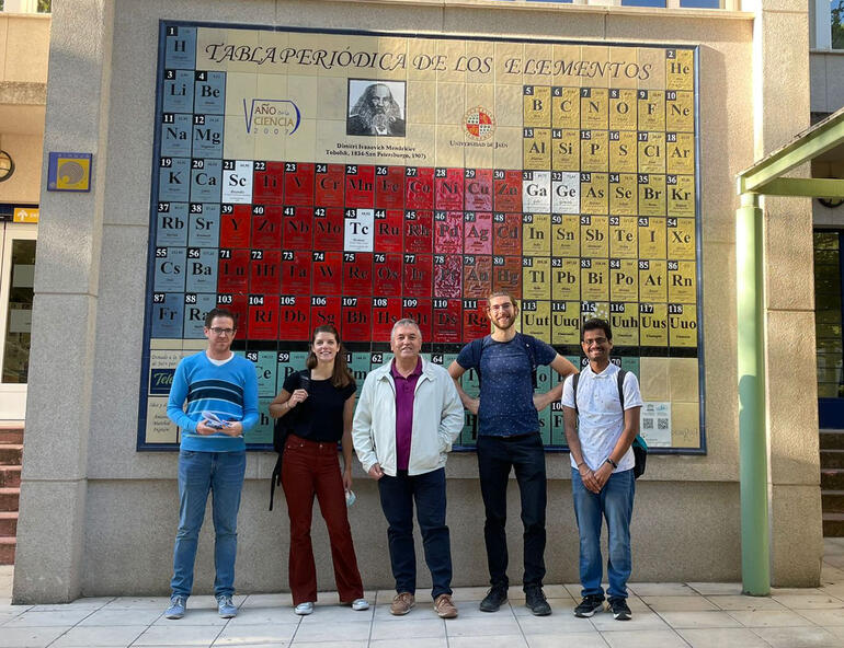 Varias personas posando delante de una tabla periódica de la universidad de Jaén