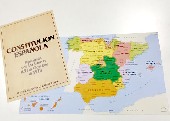 Portada de la Constitución Española, junto a un mapa político de España.