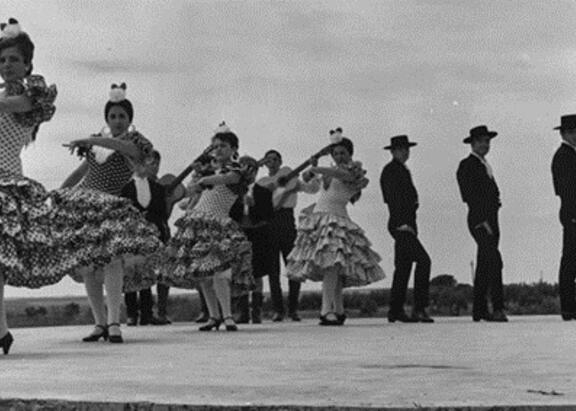 Escenario con danzantes gaditanos bailando sevillanas, posiblemente durante la celebración del XVII Concurso de Coros y Danzas de la Sección Femenina.